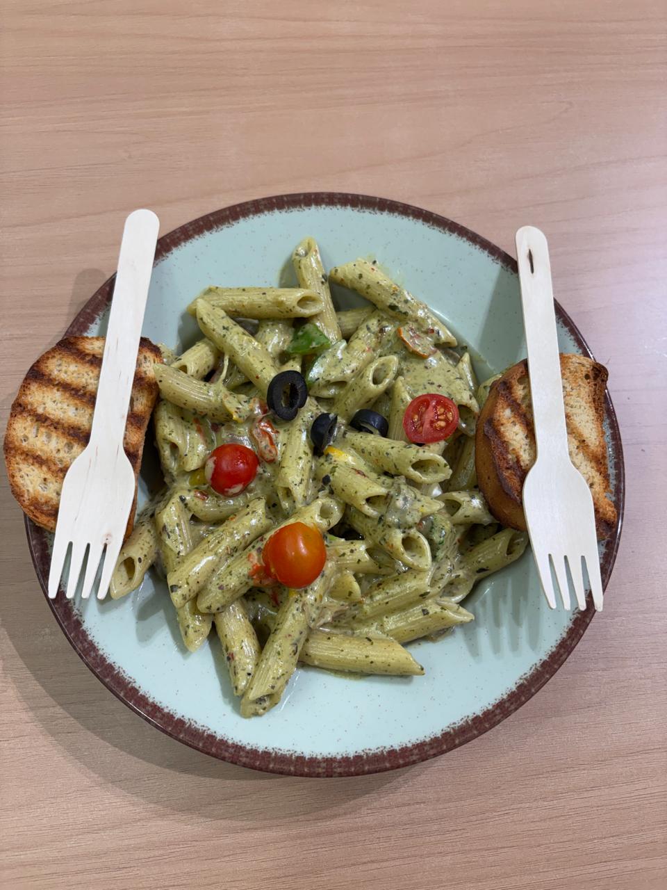 Creamy pesto basil penne pasta with cherry tomatoes and toast